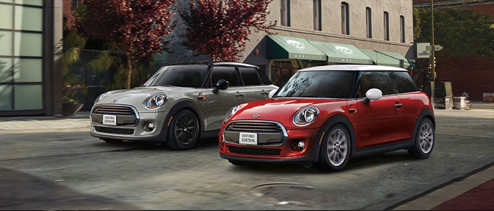 Two MINI’s driving down the street.