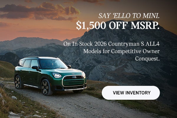 Front passenger side view of a MINI Countryman driving on a mountainous road.