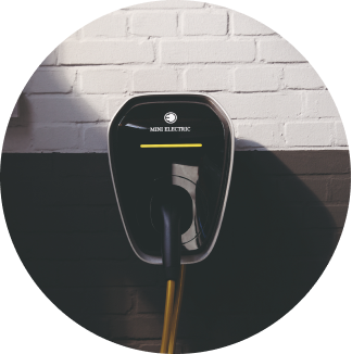 The MINI Wallbox charger on a black and white split brick wall.