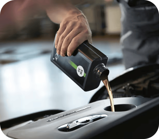 Closeup view of hand pouring motor oil into an engine with the background blurred out.