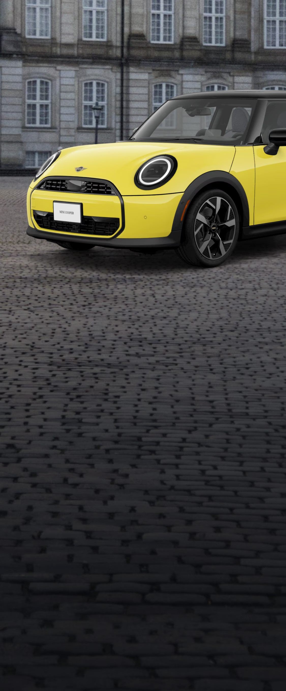 ¾ Front side view of a MINI Cooper Oxford Edition parked on a brick street in front of a building.